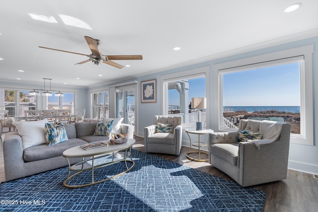 living room with crown molding, ceiling fan, plenty of natural light, and dark wood-type flooring