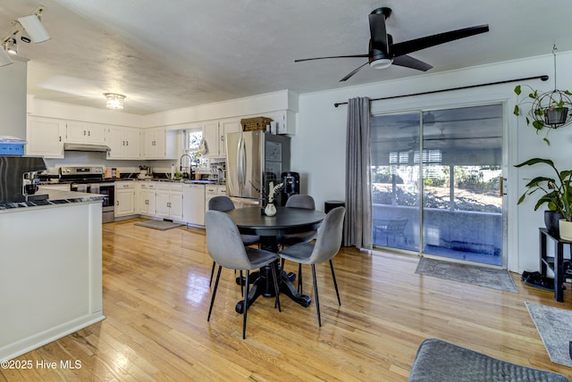 dining area featuring light wood-type flooring, ceiling fan, and sink