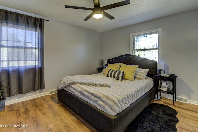 bedroom featuring ceiling fan, hardwood / wood-style floors, and a textured ceiling