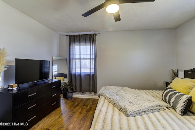 bedroom with a textured ceiling, dark hardwood / wood-style floors, and ceiling fan