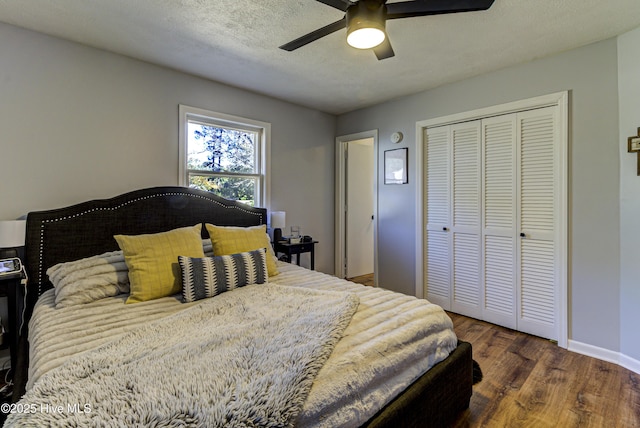 bedroom with a closet, ceiling fan, dark wood-type flooring, and a textured ceiling