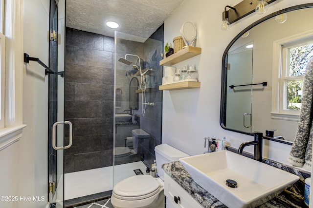 bathroom with a textured ceiling, toilet, vanity, and an enclosed shower