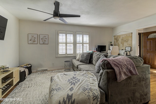 living room with hardwood / wood-style flooring, a textured ceiling, and ceiling fan