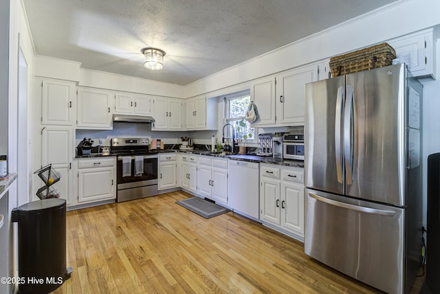 kitchen with light hardwood / wood-style flooring, appliances with stainless steel finishes, sink, white cabinets, and a textured ceiling