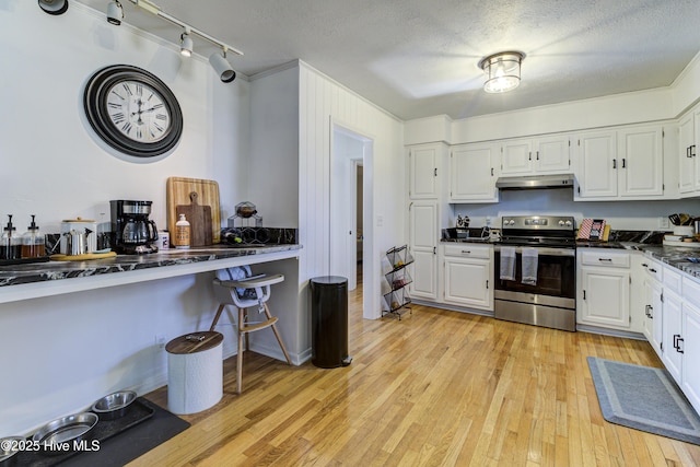 kitchen featuring stainless steel electric range oven, white cabinets, a textured ceiling, and light hardwood / wood-style floors