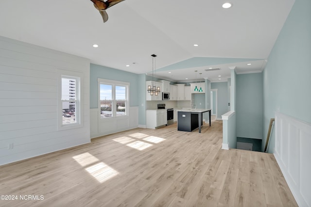 kitchen with stainless steel appliances, white cabinets, a kitchen island, pendant lighting, and vaulted ceiling