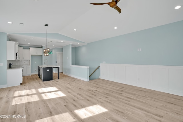 unfurnished living room featuring sink, light hardwood / wood-style floors, ceiling fan, and lofted ceiling