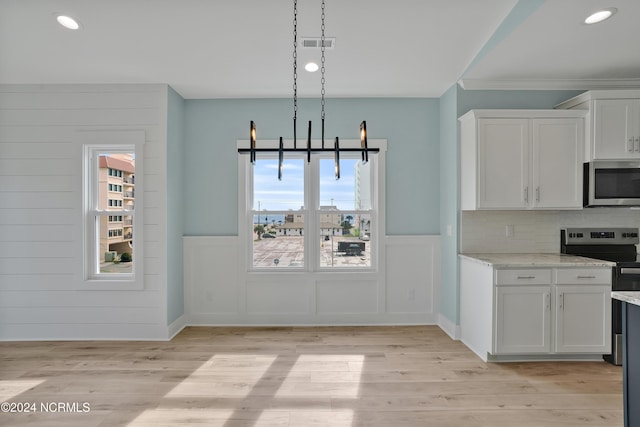 kitchen with light stone counters, plenty of natural light, white cabinets, and stainless steel appliances