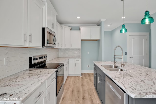 kitchen with white cabinetry, sink, pendant lighting, stainless steel appliances, and a center island with sink