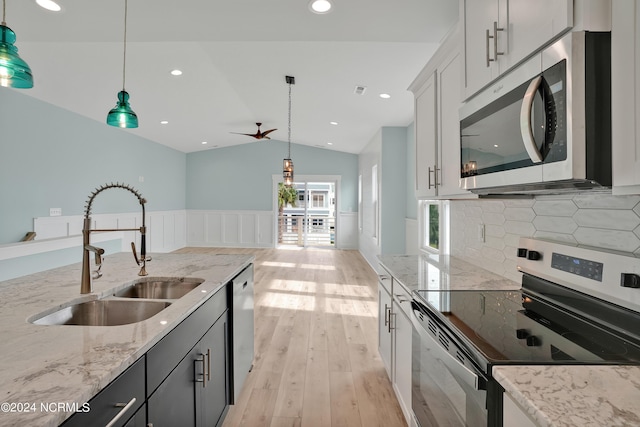 kitchen featuring sink, hanging light fixtures, appliances with stainless steel finishes, and vaulted ceiling