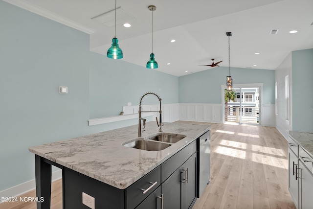 kitchen featuring light stone countertops, pendant lighting, an island with sink, sink, and vaulted ceiling