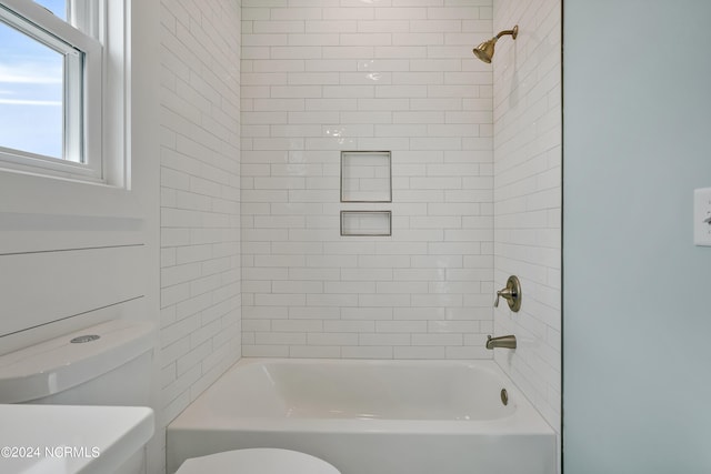 bathroom featuring toilet and tiled shower / bath combo