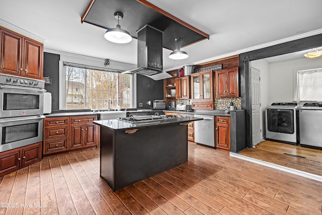 kitchen featuring a kitchen island, hardwood / wood-style floors, island range hood, separate washer and dryer, and stainless steel appliances