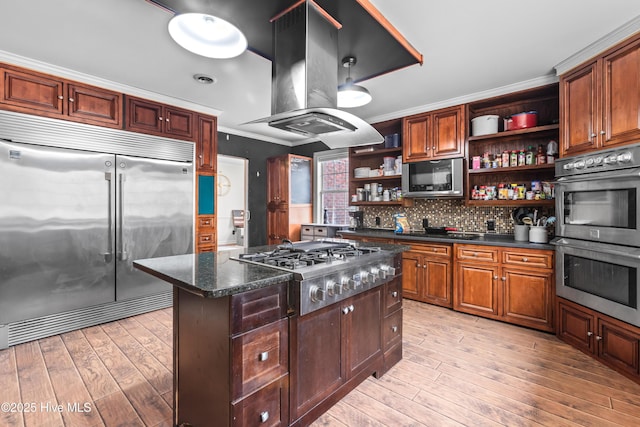 kitchen featuring appliances with stainless steel finishes, backsplash, island exhaust hood, crown molding, and light hardwood / wood-style flooring