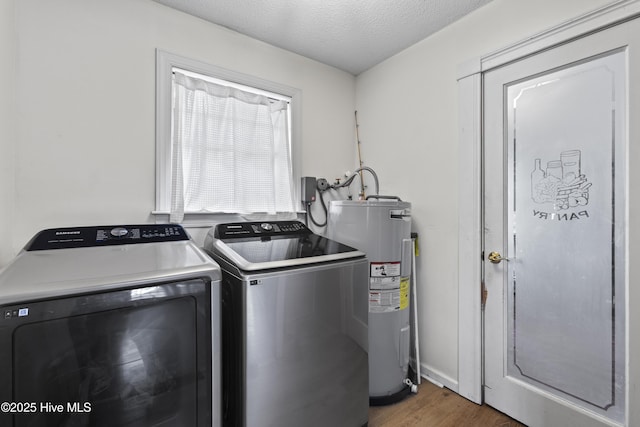 washroom featuring washing machine and clothes dryer, dark hardwood / wood-style floors, water heater, and a textured ceiling