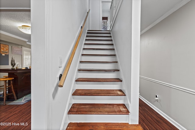 stairs featuring hardwood / wood-style floors, ornamental molding, and a textured ceiling