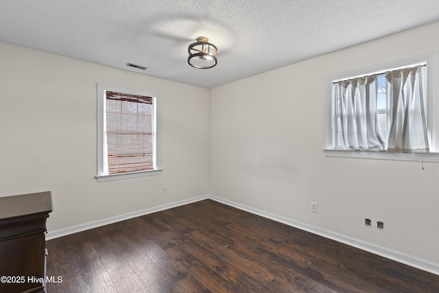 empty room featuring dark wood-type flooring and a textured ceiling