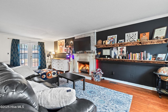 living room with crown molding, hardwood / wood-style flooring, and a large fireplace