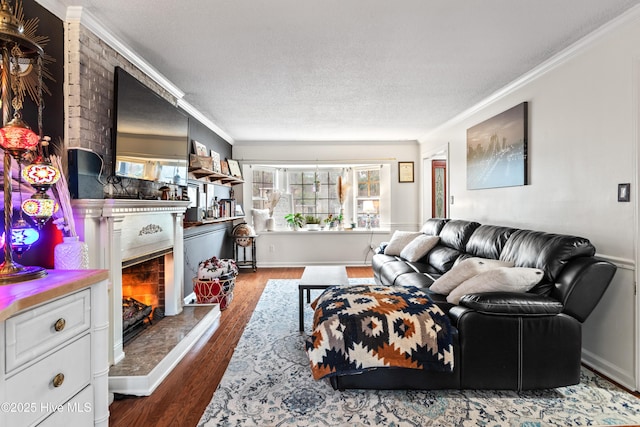 living room featuring hardwood / wood-style flooring, a large fireplace, ornamental molding, and a textured ceiling