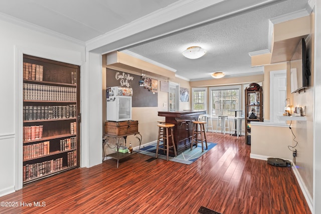 interior space featuring hardwood / wood-style floors, crown molding, a kitchen breakfast bar, and a textured ceiling