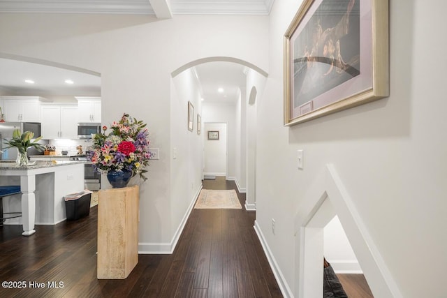 corridor with dark wood-type flooring and crown molding