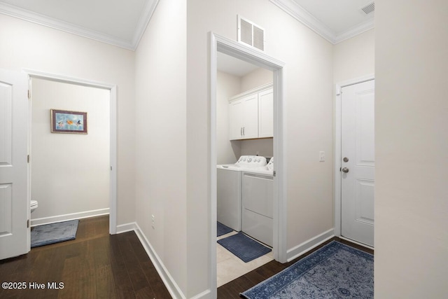 clothes washing area with independent washer and dryer, cabinets, dark wood-type flooring, and ornamental molding