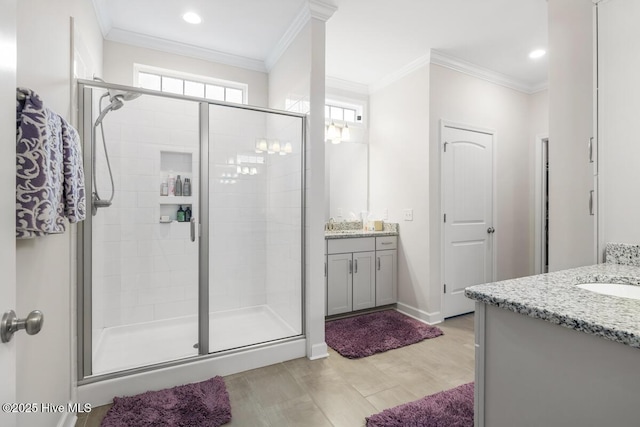 bathroom with vanity, hardwood / wood-style flooring, crown molding, and a shower with door