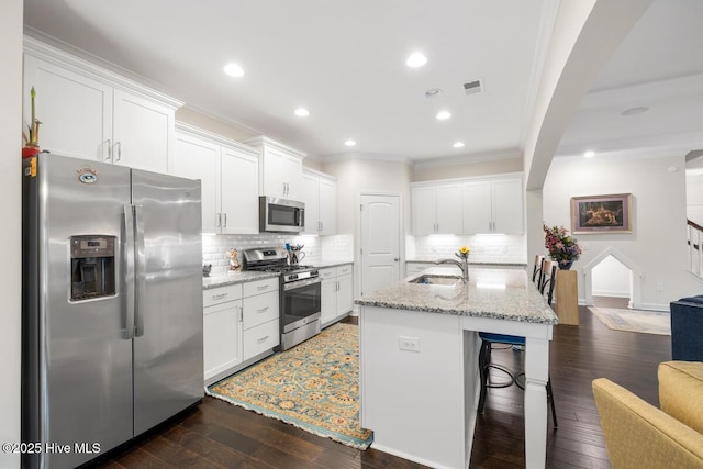 1512 Grove Ln, Wilmington, NC 28409 - kitchen with stainless steel appliances, a sink, ornamental molding, white cabinets, and dark wood-type flooring