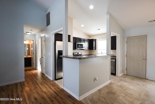 kitchen featuring hardwood / wood-style flooring, appliances with stainless steel finishes, vaulted ceiling, and a kitchen island