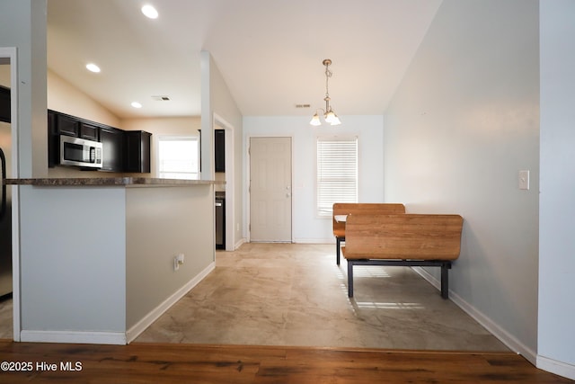 kitchen featuring lofted ceiling, decorative light fixtures, kitchen peninsula, and a notable chandelier