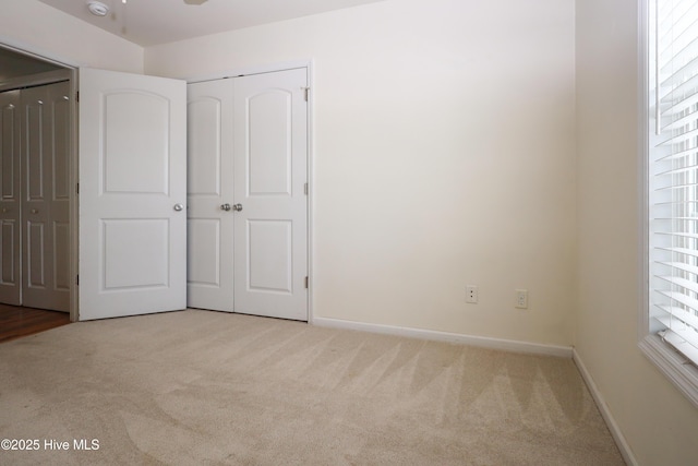 unfurnished bedroom featuring a closet and light carpet