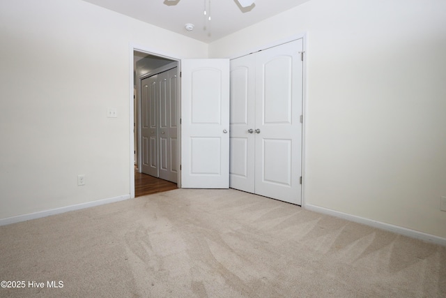 unfurnished bedroom with carpet, a closet, ceiling fan, and baseboards