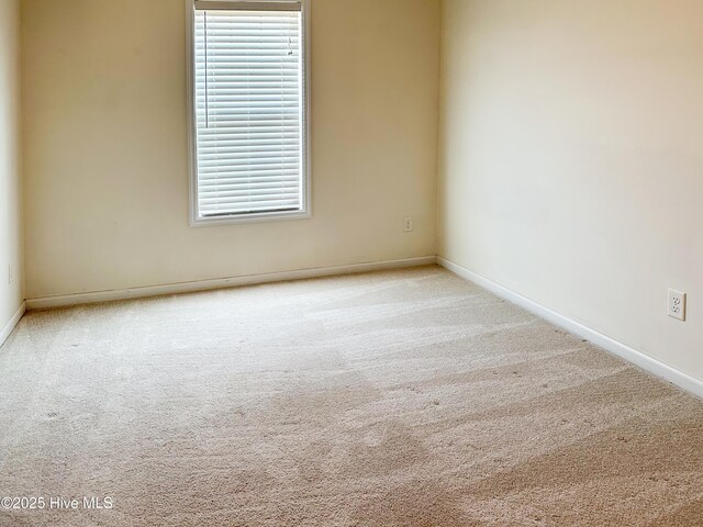 spare room featuring carpet floors and baseboards