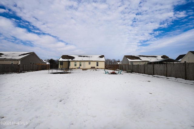 snow covered rear of property featuring a trampoline