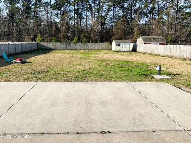 view of yard with a fenced backyard, a storage unit, and an outbuilding