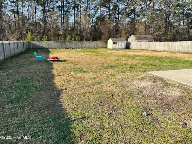 view of yard with a storage shed, a fenced backyard, and an outbuilding