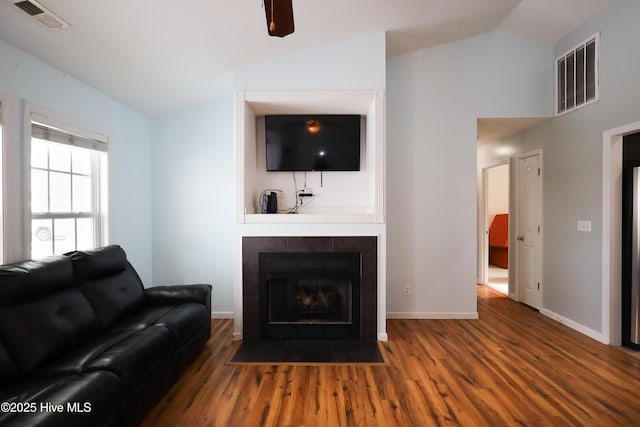 living room with a tile fireplace, wood-type flooring, and lofted ceiling