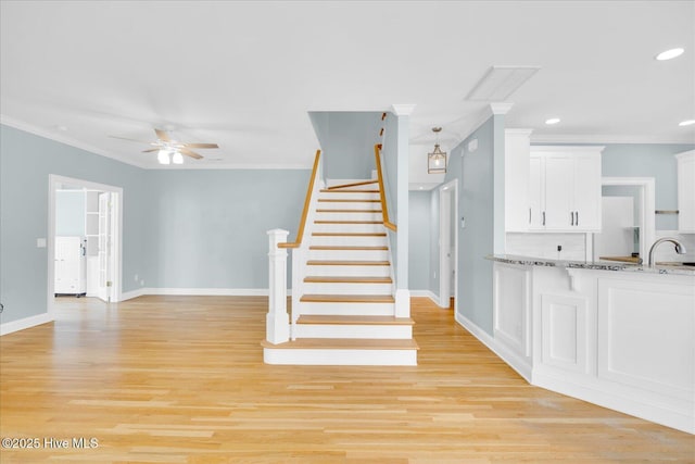 staircase with sink, hardwood / wood-style flooring, ceiling fan, and ornamental molding