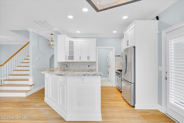 kitchen with light wood-type flooring, tasteful backsplash, white cabinetry, light stone countertops, and stainless steel appliances