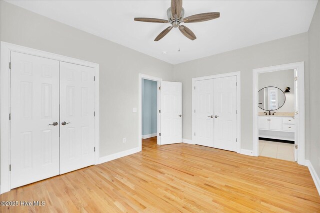 unfurnished bedroom with multiple closets, ceiling fan, connected bathroom, and wood-type flooring