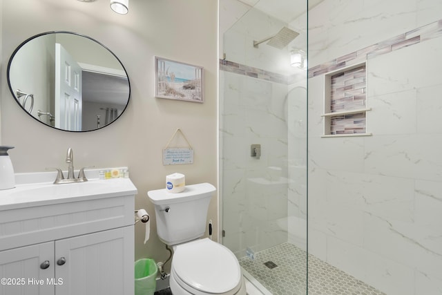 bathroom with vanity, tiled shower, and toilet