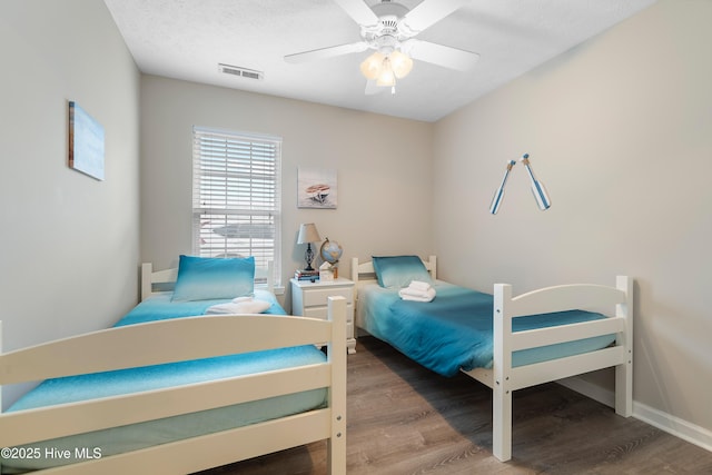 bedroom with ceiling fan, wood-type flooring, and a textured ceiling