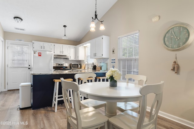 dining room with high vaulted ceiling, sink, and light wood-type flooring