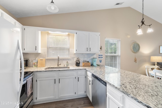 kitchen with appliances with stainless steel finishes, sink, pendant lighting, and white cabinets