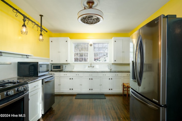 kitchen featuring hanging light fixtures, white cabinetry, appliances with stainless steel finishes, and dark hardwood / wood-style floors