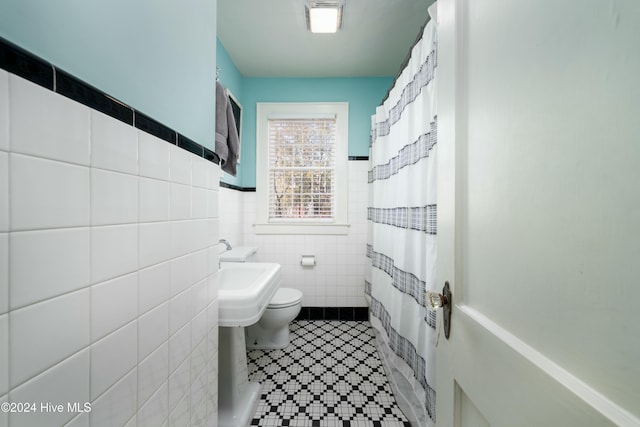 bathroom with tile walls, tile patterned flooring, a shower with curtain, and toilet