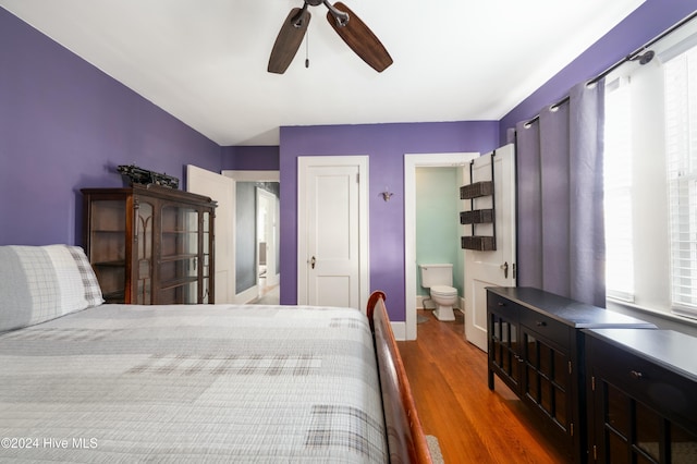 bedroom with dark wood-type flooring, ceiling fan, and connected bathroom