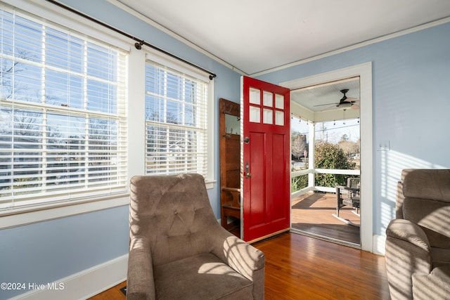 living area featuring crown molding, dark wood-type flooring, and ceiling fan