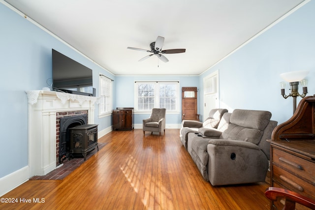 living room with hardwood / wood-style flooring, crown molding, a wood stove, and ceiling fan