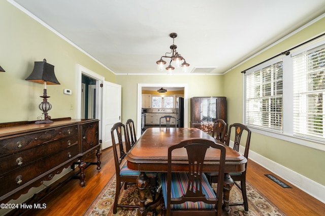 dining room featuring a notable chandelier, dark wood-type flooring, and ornamental molding